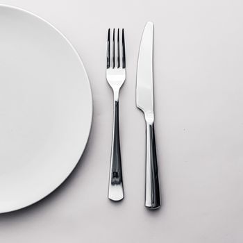 Empty plate and cutlery as mockup set on white background, top tableware for chef table decor and menu branding design