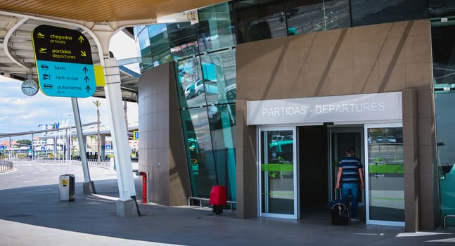 Faro, Portugal - May 3, 2018: Exterior view of Faro International Airport where passengers are walking with their suitcases on a spring day