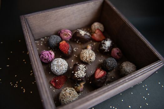 handmade sugar free and gluten free fruit and chocolate candies in a wooden box and black background