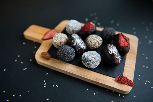 handmade sugar free and gluten free fruit and chocolate candies on a wooden board and black background