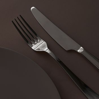 Empty plate and cutlery as mockup set on dark brown background, top tableware for chef table decor and menu branding design