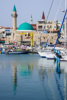 ACRE, ISRAEL - MARCH 06, 2014: Fishing boats, yachts and nearby monuments, in the fishing harbor in the old city of Acre, Israel. Acre is one of the oldest continuously inhabited sites in the world.