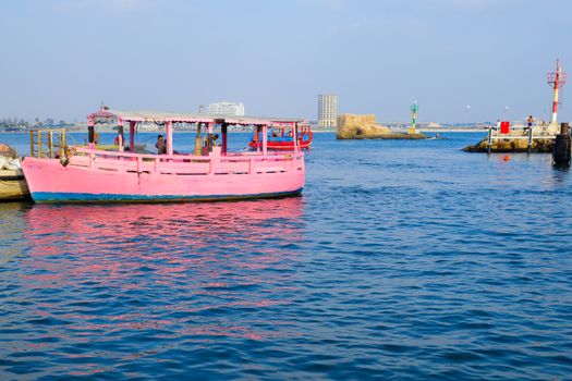 ACRE, ISRAEL - AUGUST 03, 2016: Scene of a boat in the fishing harbor, the tower of the flies, locals and tourists, in the old city of Acre, Israel