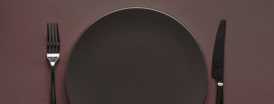 Empty plate and cutlery as mockup set on dark brown background, top tableware for chef table decor and menu branding design