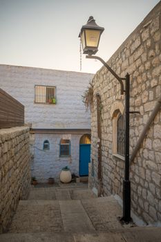 SAFED, ISRAEL - SEPTEMBER 14, 2016: An alley in the Jewish quarter of the old city, at sunset, with various signs, in Safed (Tzfat), Israel