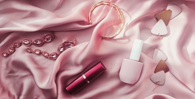 Fashionable and stylish accessories, jewelry and make-up products on pink silk background, beauty and fashion concept