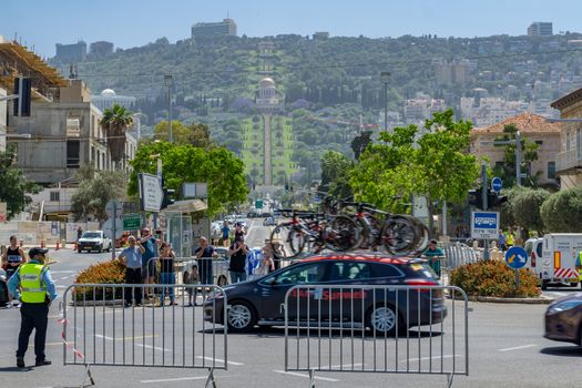 HAIFA, ISRAEL - MAY 05, 2018: Scene of stage 2 of 2018 Giro d Italia, with team car and spectators, and the German Colony, Bahai gardens and shrine in the background. Haifa, Israel