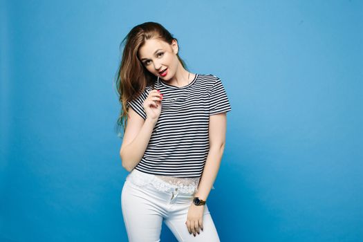 Swag and fashionable girl in sunglasses wearing in striped blouse and white jeans, holding hand on waist and seductive posing.Stylish trendy beautiful woman with perfect haircut, red lips after salon.