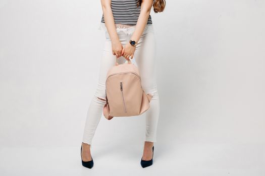 Fashionable and stylish woman with long wavy hair,red lips making duck face, surprised looking up. Girl wearing in blouse, white jeans, with leather bag, dreaming and touching face by finger. Fashion and advertising concept.