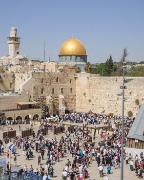 JERUSALEM, ISRAEL - APRIL 17, 2014: The Western Wall crowded with Passover prayers, and the Dome of the Rock in the background, in the old city of Jerusalem, Israel