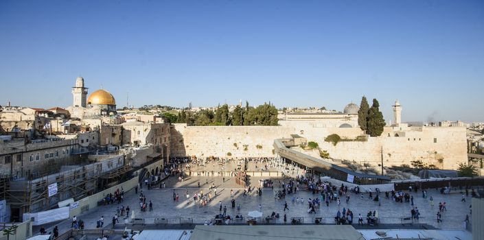 JERUSALEM, ISRAEL - APRIL 18, 2014: The Western Wall crowded with Passover prayers, and the El-Aksa Mosque and the Dome of the Rock in the background, in the old city of Jerusalem, Israel