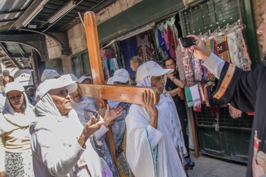 JERUSALEM - APRIL 18, 2014: Pilgrims from all over the world commemorating the crucifixion of Jesus Christ by carrying a cross along via dolorosa, on good Friday, in the old city of Jerusalem, Israel