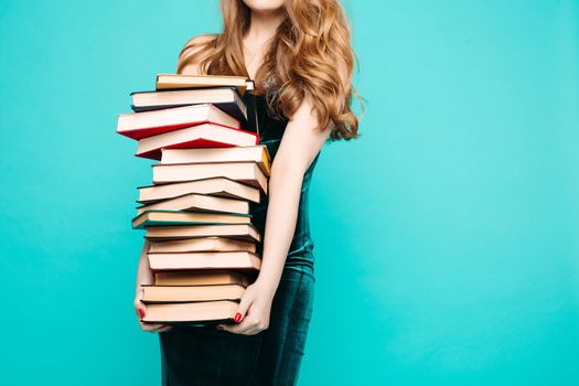 Portrait of emotionally shocked sexy teacher in dress with lace, eyeglasses, holding many books and surprised looking at camera. Young teacher or student screaming. Blue studio background.