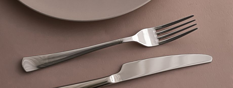 Empty plate and cutlery as mockup set on brown background, top tableware for chef table decor and menu branding design