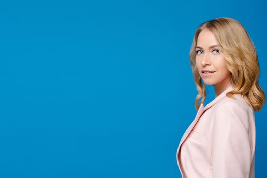 Beautiful caucasian woman with light wavy hair in a white shirt isolated on blue background