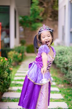 Portrait of cute smiling little girl in princess costume standing on the footpath