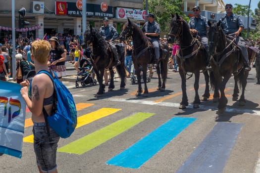 HAIFA, ISRAEL - JUNE 22, 2018: Zebra crossing painted in the rainbow colors, policemen on horses, and other participants, in the annual pride parade of the LGBT community, in Haifa, Israel