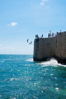 ACRE, ISRAEL - JUNE 27, 2009: Young men jumps to the sea from the top of the ancient walls of Acre, Israel. Acre is one of the oldest continuously inhabited sites in the world.