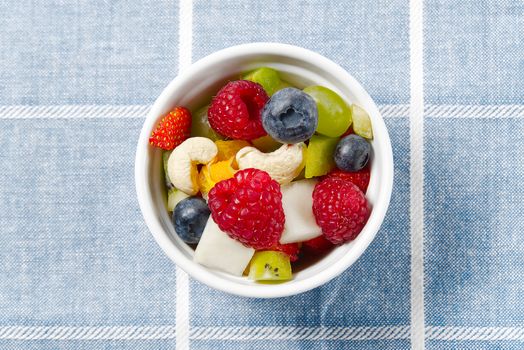 Three bowls with fruit salad. Fresh fruit salad on white bowl. Mixed fruit in white bowl healthy food style. Useful fruit salad of fresh fruits and berries on pink background.