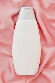 Blank label cosmetic container bottle as product mockup on pink silk background, hygiene and healthcare