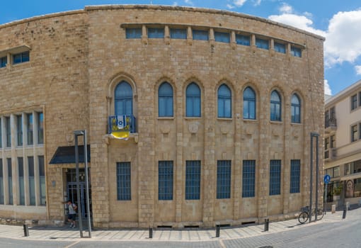 HAIFA, ISRAEL - JULY 21, 2018: View of the historic Anglo Palestine APAK Bank building, with visitors and other buildings, in Haifa, Israel