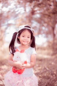 Cute little asian girl with a doll in the park