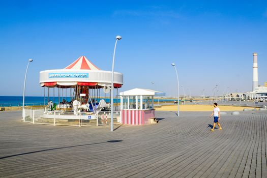 TEL-AVIV, ISRAEL - NOVEMBER 24, 2016: Scene with a restored carrousel, a commercial area, the Reading power station chimney, and visitors, in Tel-Aviv Port, Tel-Aviv, Israel