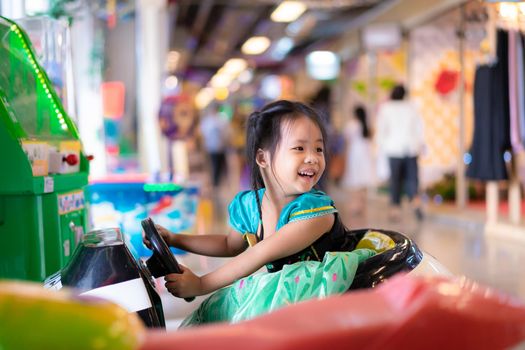 little asian girl in princess costume ride on toy car in mall