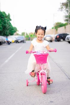 Cute little asian girl riding a bicycle to exercise on the street, kids sport and active lifestyle