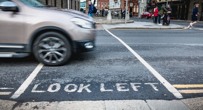 Dublin, Ireland - February 11, 2019: Look Left painted in white on the road on a pedestrian crossing in the city center on a winter day