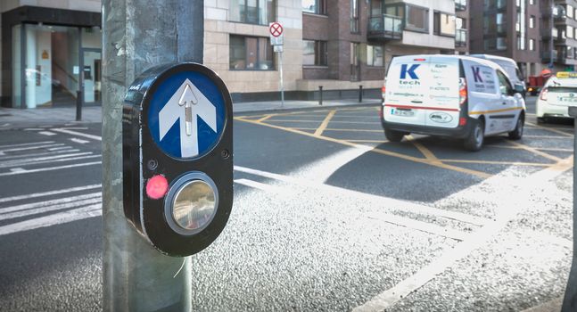 Dublin, Ireland - February 11, 2019: Button to activate pedestrian crossing on the road on a pedestrian crossing in the city center on a winter day