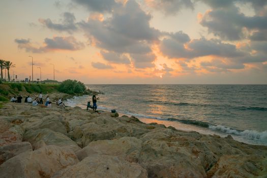 HAIFA, ISRAEL - AUGUST 06, 2018: Sunset beach scene with local fisherman and other locals, in Haifa, Israel
