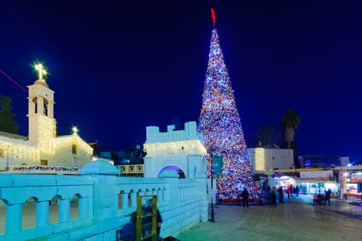 NAZARETH, ISRAEL - DECEMBER 20, 2016: Christmas scene of Mary Well square, with the Greek Orthodox Church of the Annunciation, a Christmas tree, locals and tourists, in Nazareth, Israel