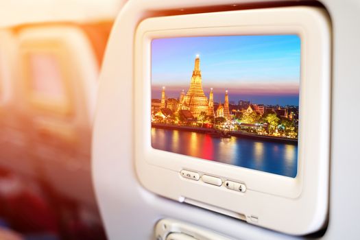Aircraft monitor in passenger seat on Wat Arun night view Temple in bangkok, Thailand background