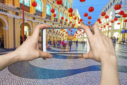 Girl taking pictures on mobile smart phone in Senado Square nigth view of Macau.