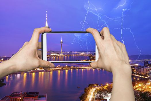 Taking pictures on mobile smart phone in Night view of Macau Tower in Twilight Time