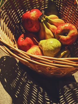 Organic apples, pears and bananas on rustic in a wicker basket, fruits farming and agriculture