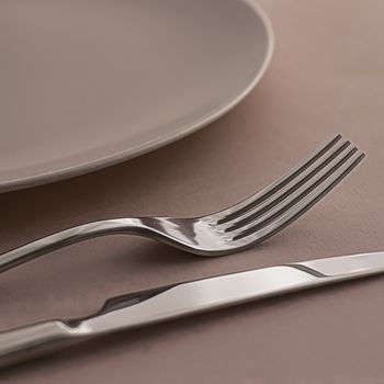 Empty plate and cutlery as mockup set on brown background, top tableware for chef table decor and menu branding design