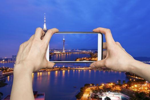 Taking pictures on mobile smart phone in Night view of Macau Tower in Twilight Time