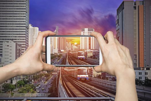 Girl taking pictures on mobile smart phone in Sky Train at bangkok,thailand