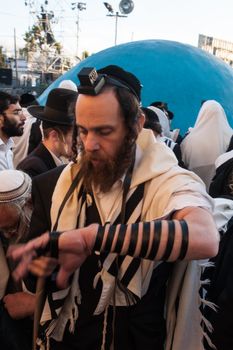 MERON, ISRAEL - MAY 18, 2014: An orthodox Jew putting on his tefillin, near the tomb of Rabbi Shimon, at the annual hillulah of Rabbi Shimon Bar Yochai, in Meron, on Lag BaOmer Holiday.