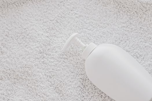 Blank label cosmetic container bottle as product mockup on white towel background, hygiene and healthcare