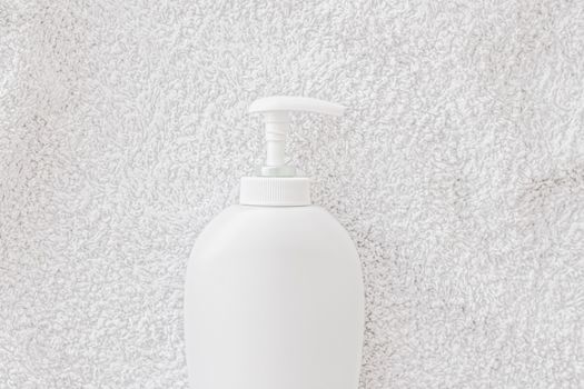 Blank label cosmetic container bottle as product mockup on white towel background, hygiene and healthcare