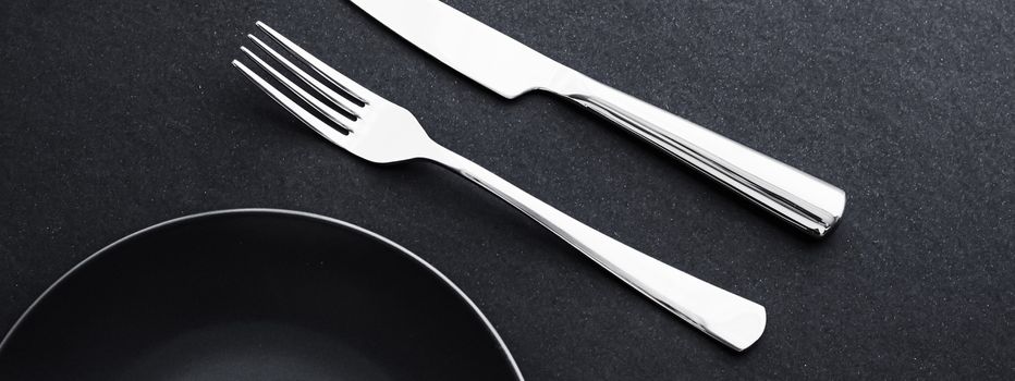 Empty plates and silverware on black background, premium tableware for holiday dinner, minimalistic design and diet concept