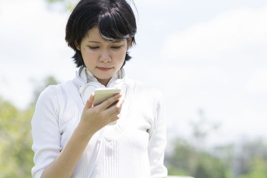 Stressed asian woman looking at mobile phone. Blur building background.