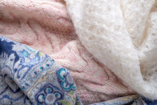 Soft folds of a warm pink knitted woolen pullover and a blue decorated scarf with a white goat fluff scarf to be used as background