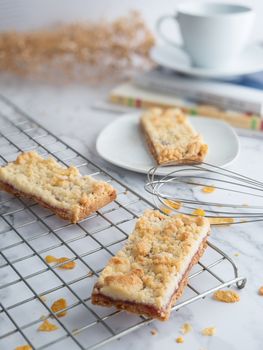 jam crumble bar on cake rack and white dish, decorated with egg whisk, selective focus. fresh homemade bakery concept