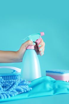 woman hand holding cleaning spray blue plastic bottle detergent isolated on blue background with cleaning tools product supplies