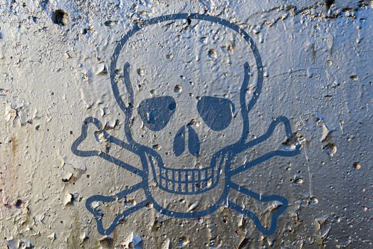 A skull as poison symbol on a silver paint texturized wall