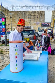 Safed, Israel - March 10, 2020: Jewish men and women in costumes read the megillah (Scroll of Esther), it is a tradition of Purim (Jewish Holiday). In the old city of Safed (Tzfat), Israel